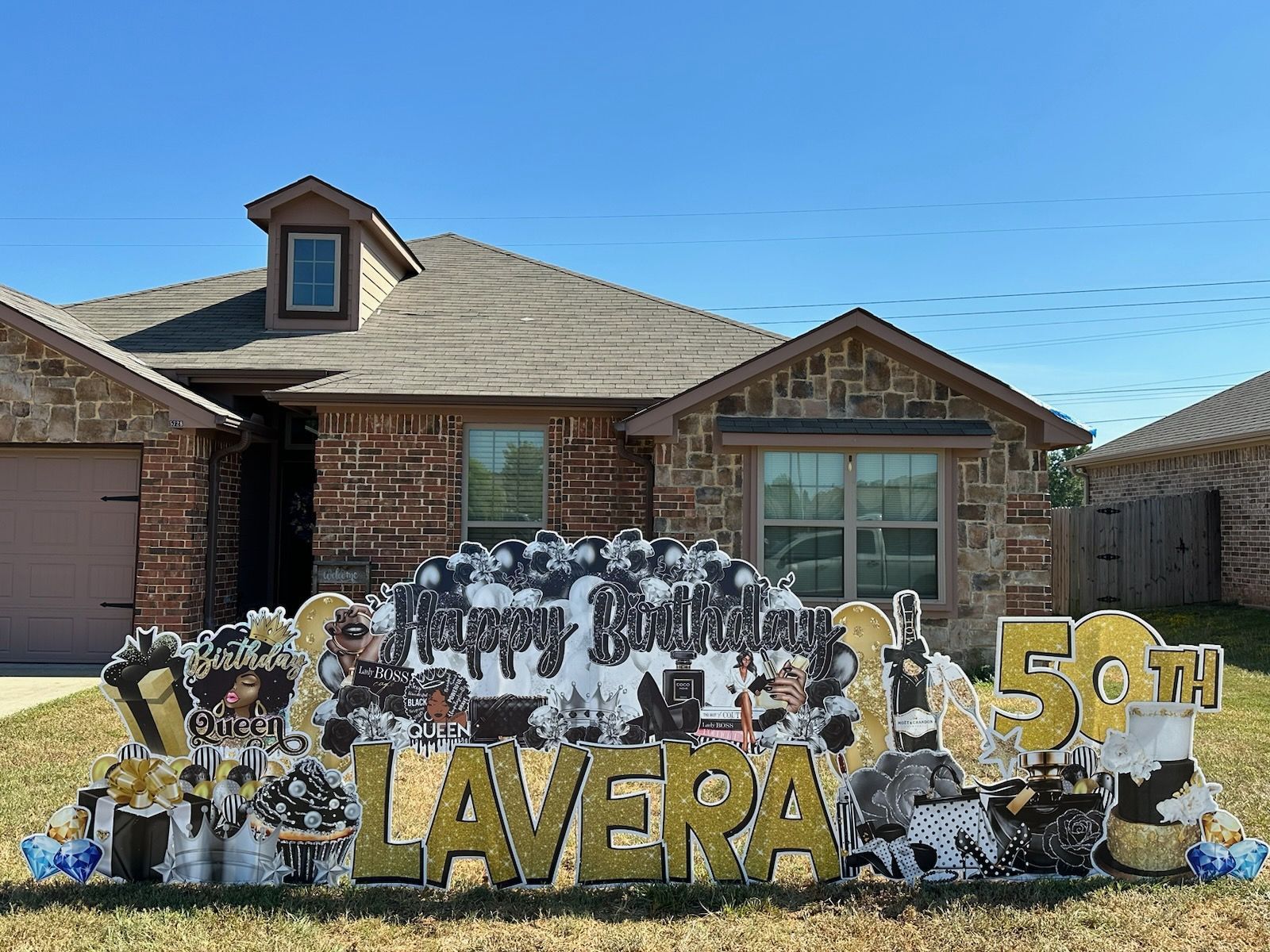 A 50th birthday sign is in front of a brick house.