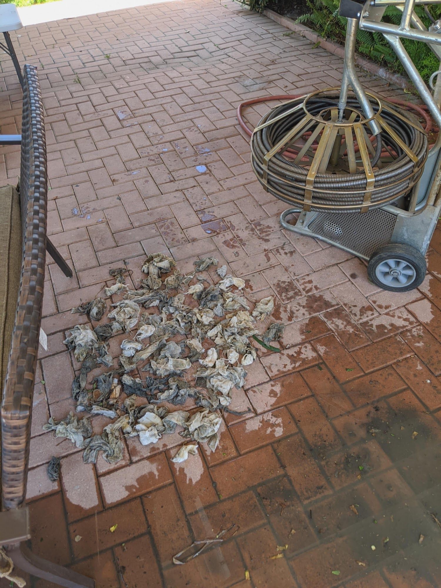 Pile of debris, likely from a drain, on a brick patio next to a cable machine.