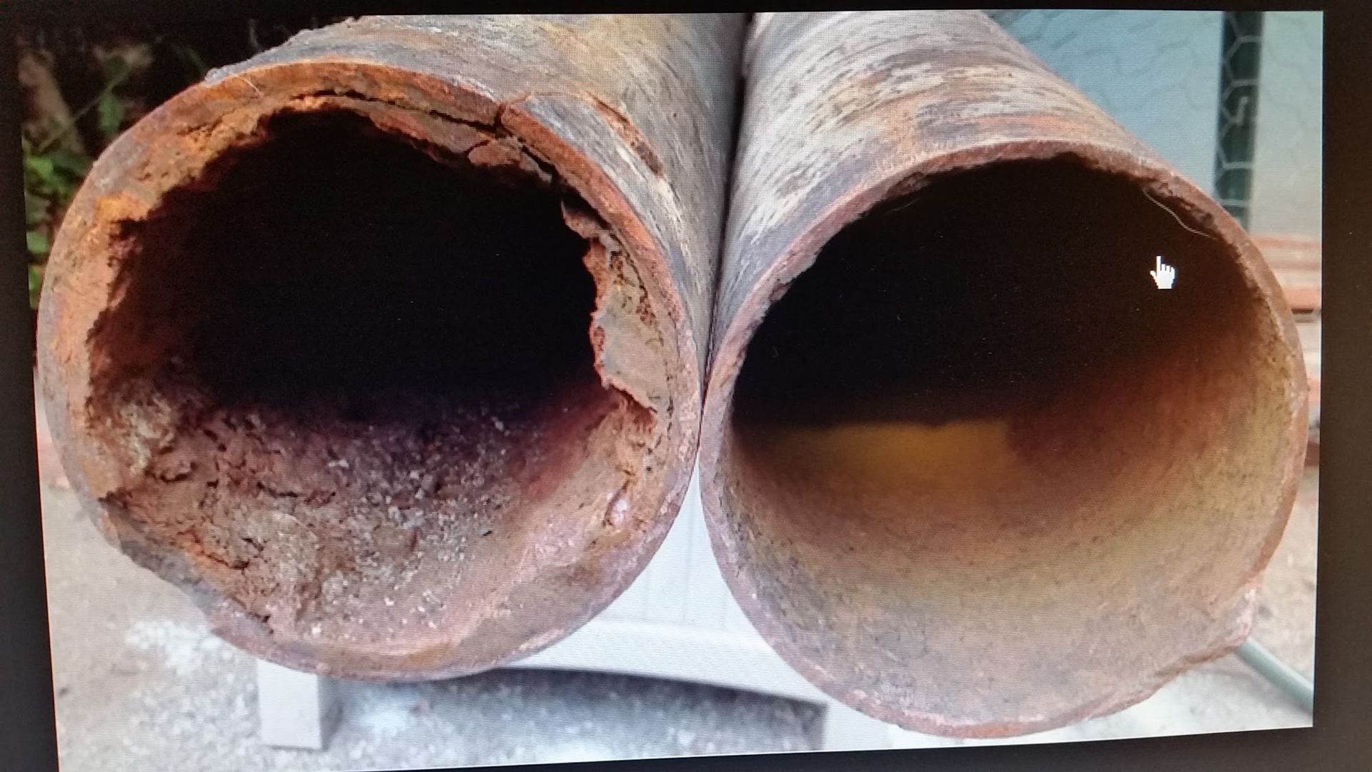 Two rusted pipes, one severely corroded, the other less so, side-by-side.