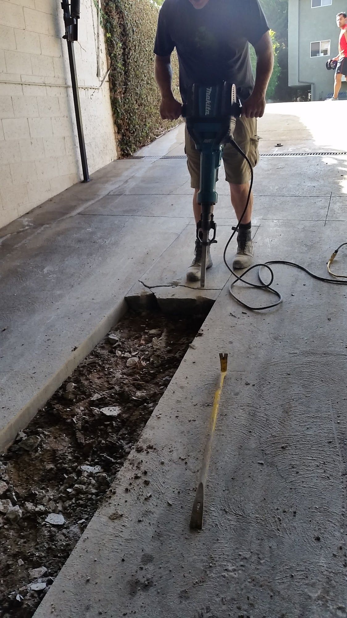 Person using a jackhammer to break up concrete in a driveway.