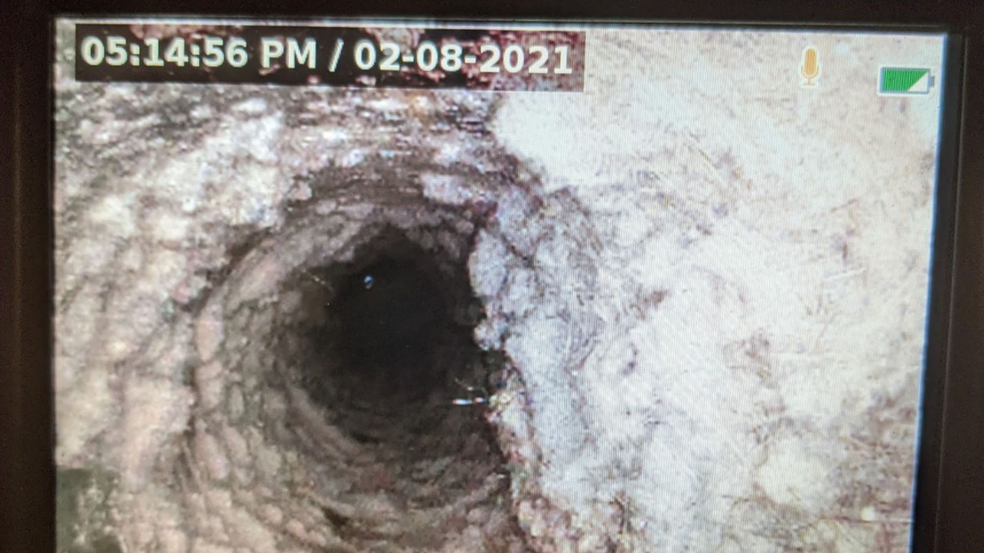 View from within a dark, cylindrical well with textured, light-colored walls. Date and time stamp in upper left.