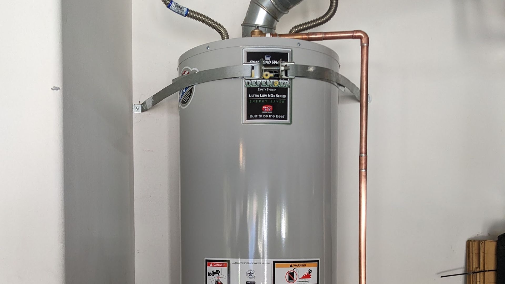 Gray water heater with copper pipes in a room.