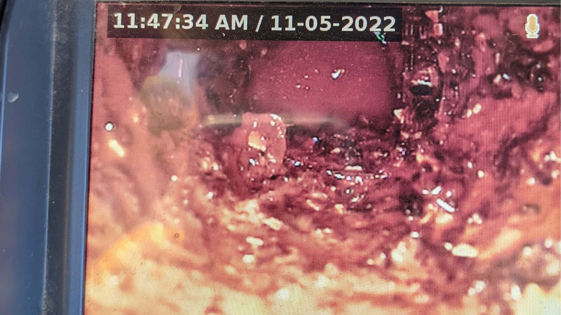 Internal pipe inspection: reddish-brown, debris with a small, light-colored object inside. Timestamp: 11:47 AM, Nov 5, 2022.