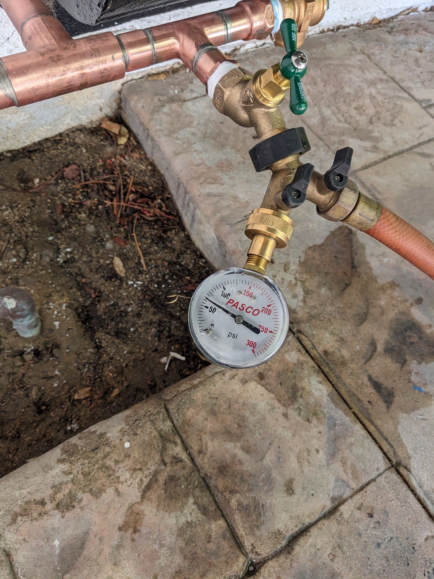 Water pressure gauge connected to outdoor plumbing on a patio.