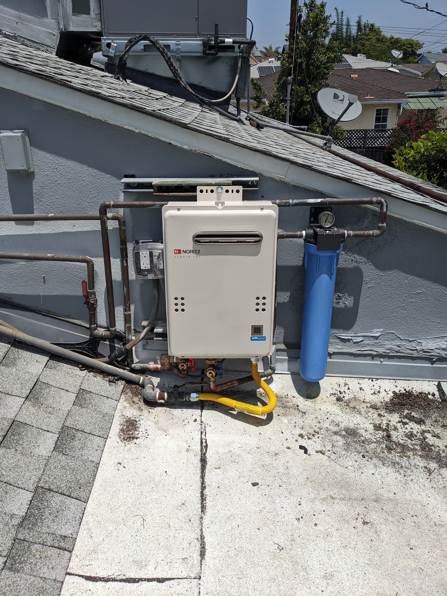 A tankless water heater, water filter, and gas lines are mounted on a rooftop.