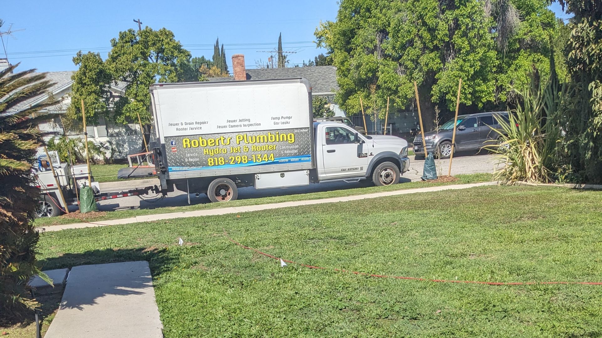 A white delivery truck parked on the street with “Horizon Gardening” signage. Green grass and trees frame the scene.