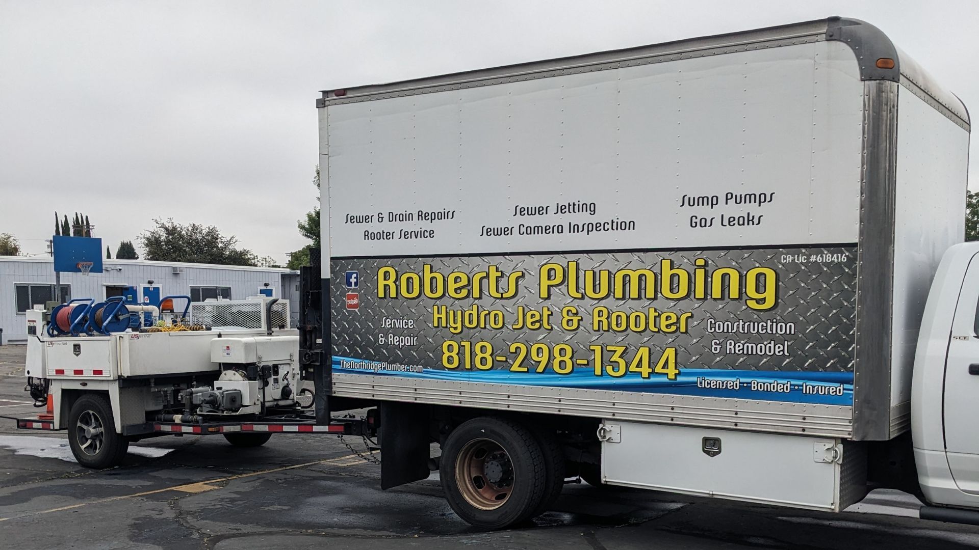 White Roberts Plumbing truck and trailer parked, company logo visible, phone number: 818-298-1344.