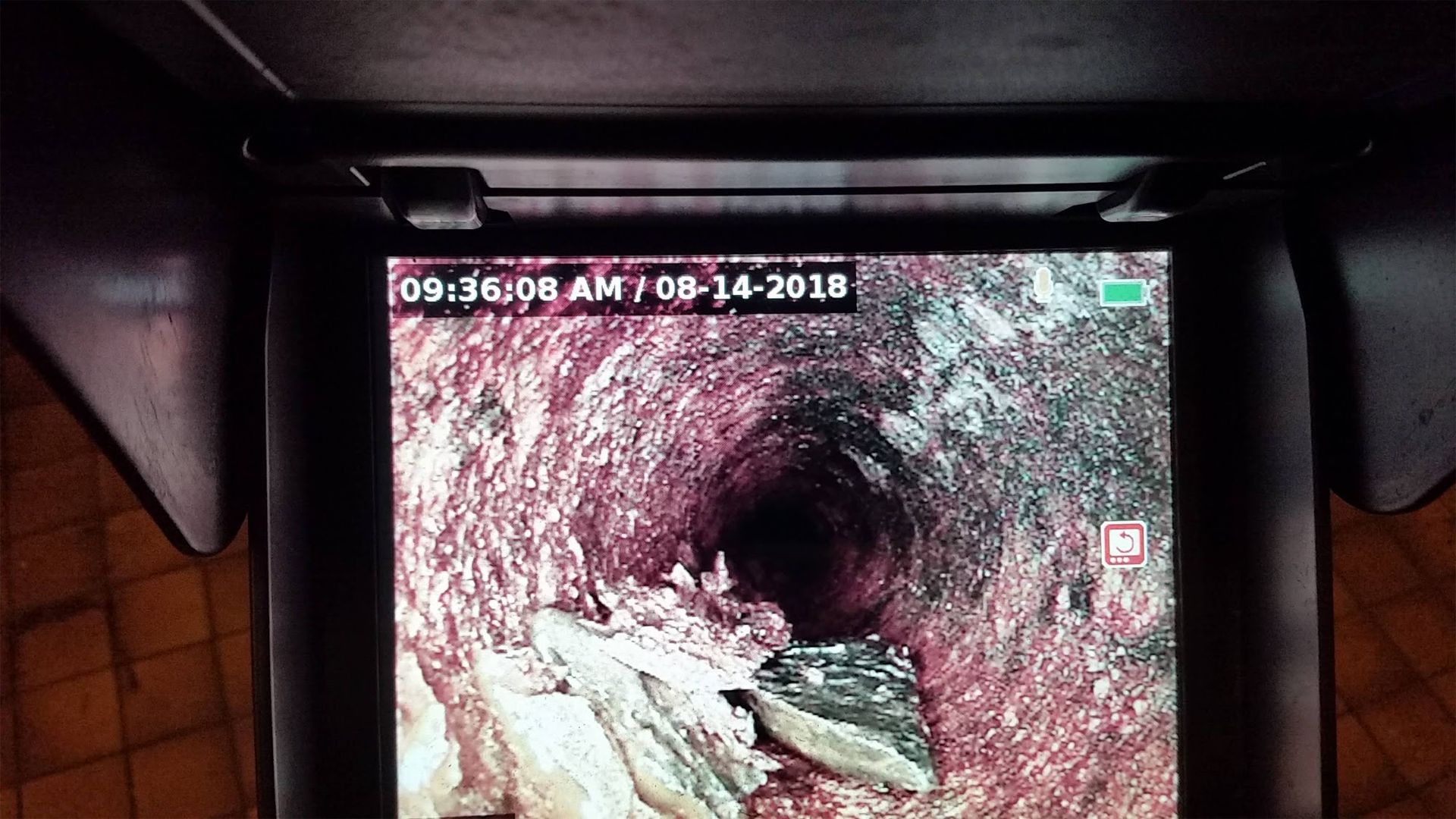 A screen showing a camera view inside a pipe. Debris is visible. Timestamp: 09:56 AM, 08-14-2018.