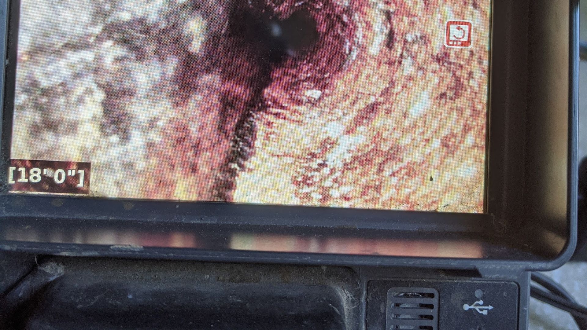 Close-up of a monitor displaying a pipe's interior; swirling brown, red, and black textures; [18'0