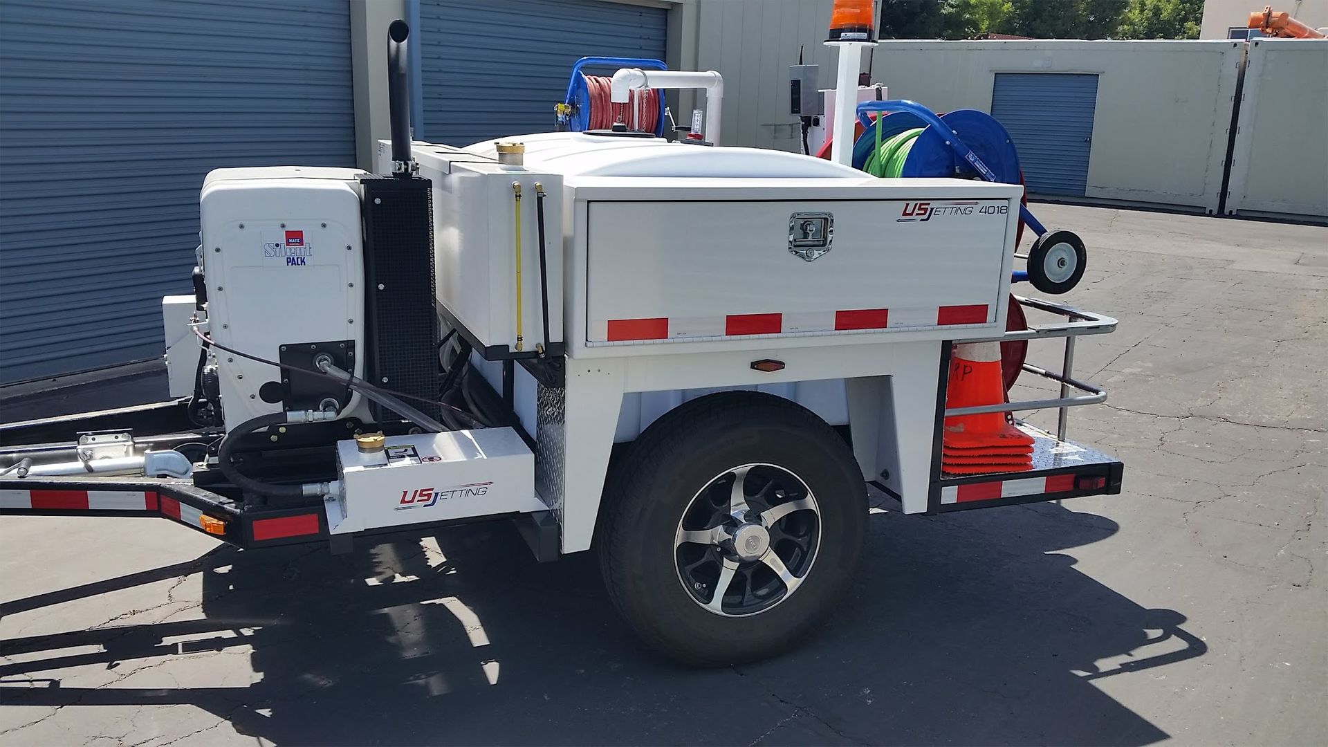 White road striping trailer with orange safety lights, parked outdoors.