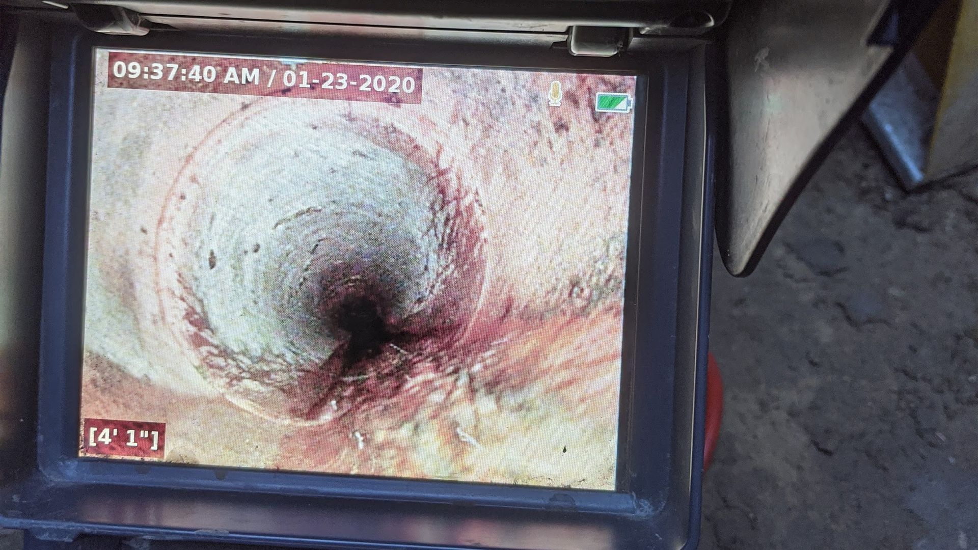 Monitor displaying interior of a pipe; dark spot at center. The date/time display on top left.
