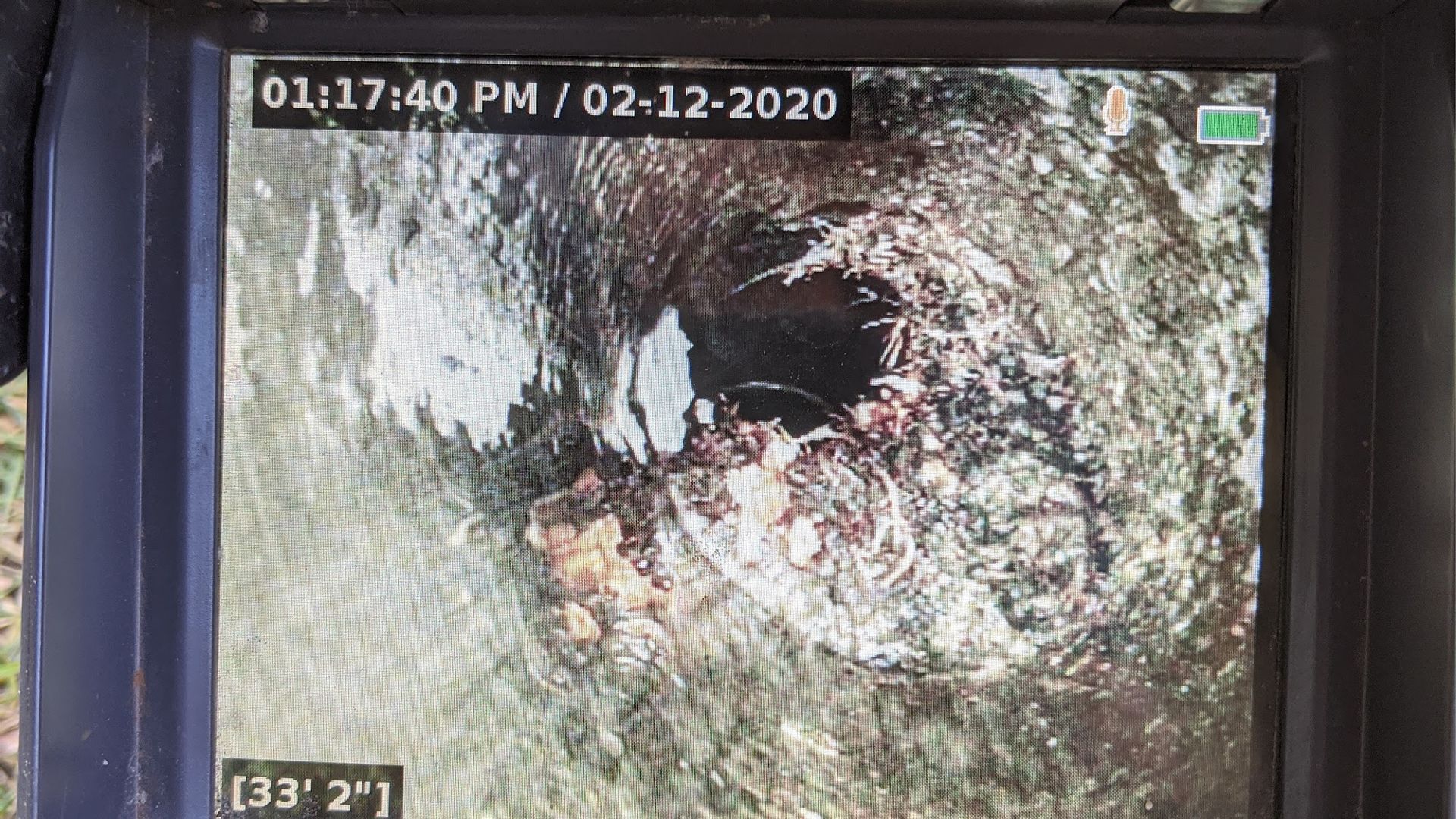 Camera view inside a pipe, showing debris and water with time/date stamp (02-12-2020).