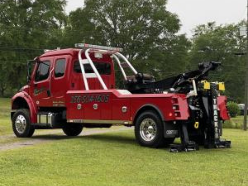 Red tow truck parked on grass.