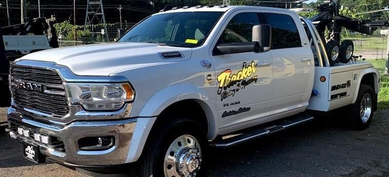 White tow truck with black graphics, parked outdoors.