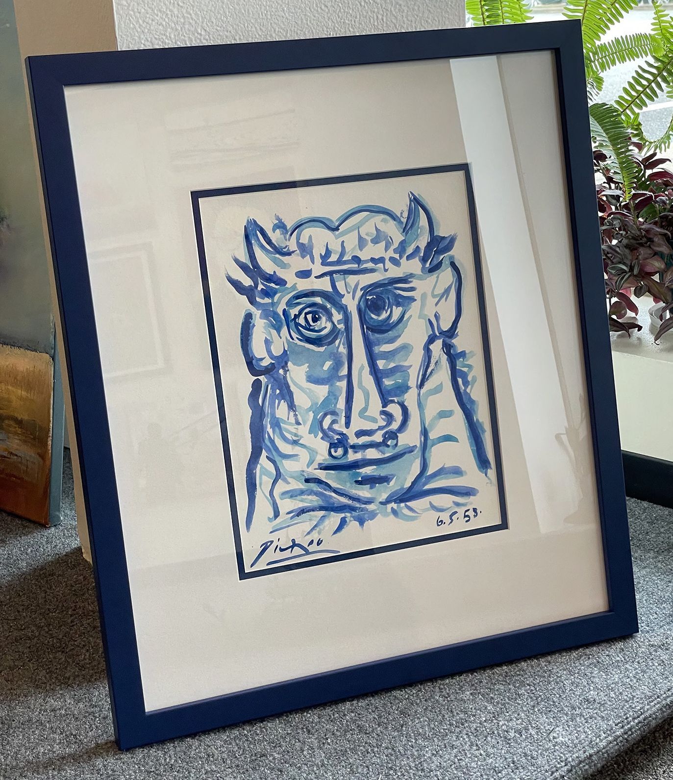 A blue and white painting of a bull 's face in a blue frame