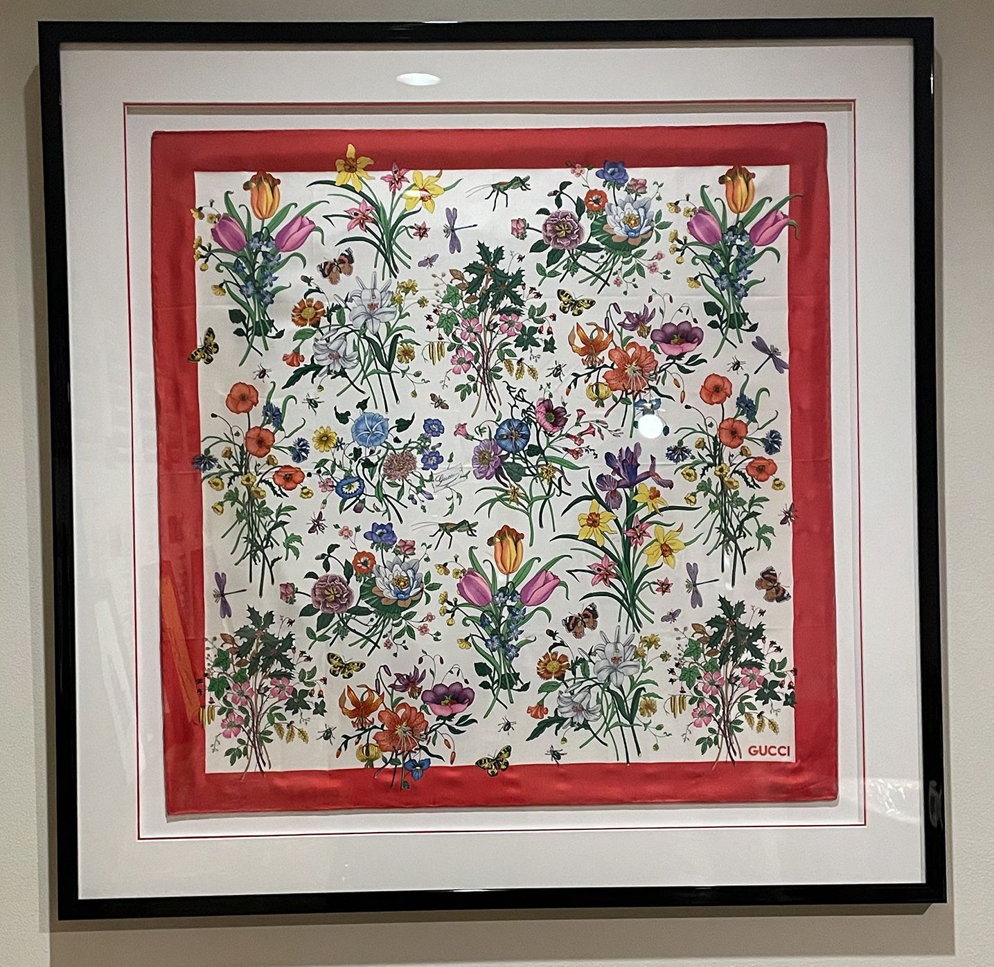 A framed picture of flowers with a red border