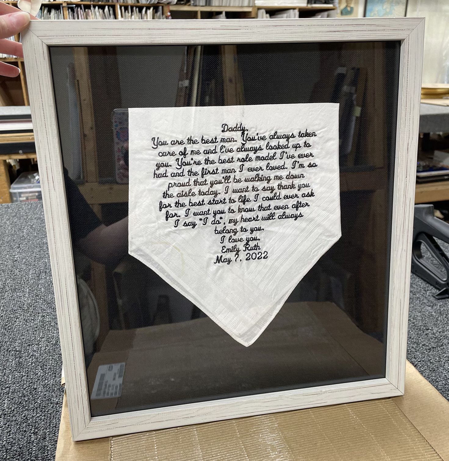 A person is holding a framed piece of paper that says daddy on it