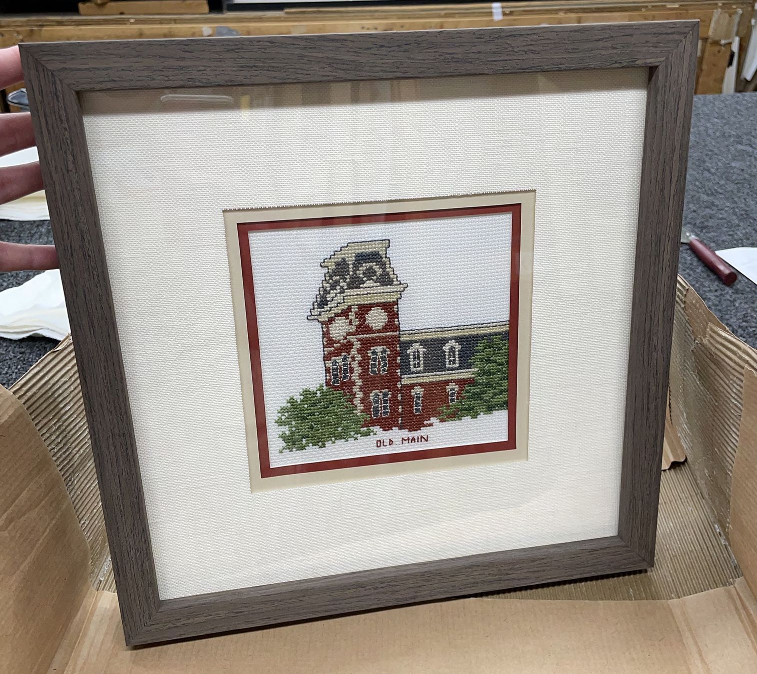A framed cross stitch picture of a clock tower