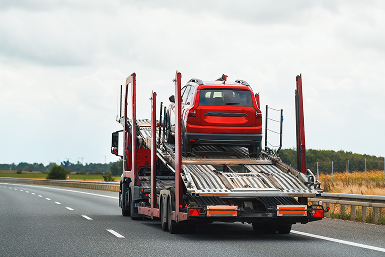 Red SUV being carried by red semi for towing | CL Enterprises