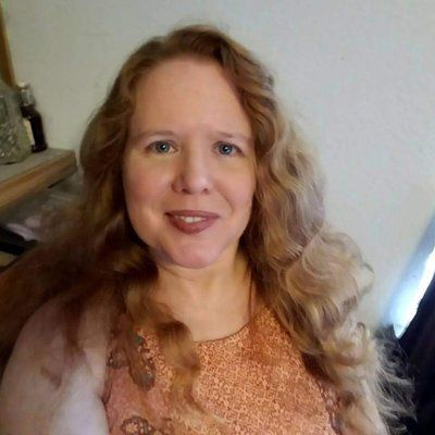 A woman with long red hair is smiling for the camera.