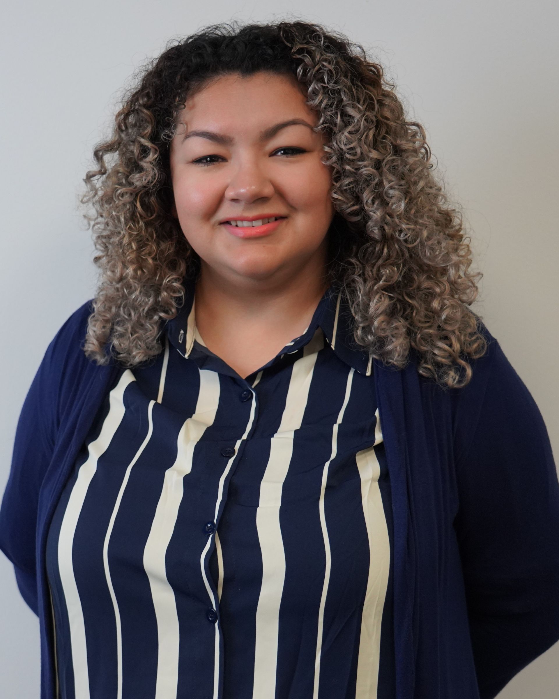 A woman with curly hair wearing a blue and white striped shirt