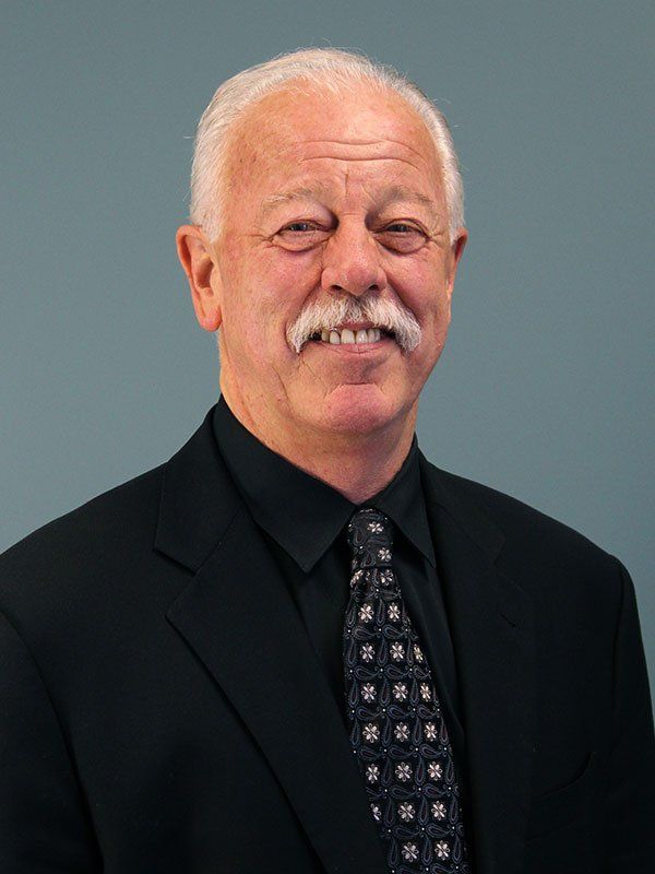 A man with a mustache is wearing a suit and tie