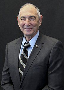 A man in a suit and tie is smiling for the camera.