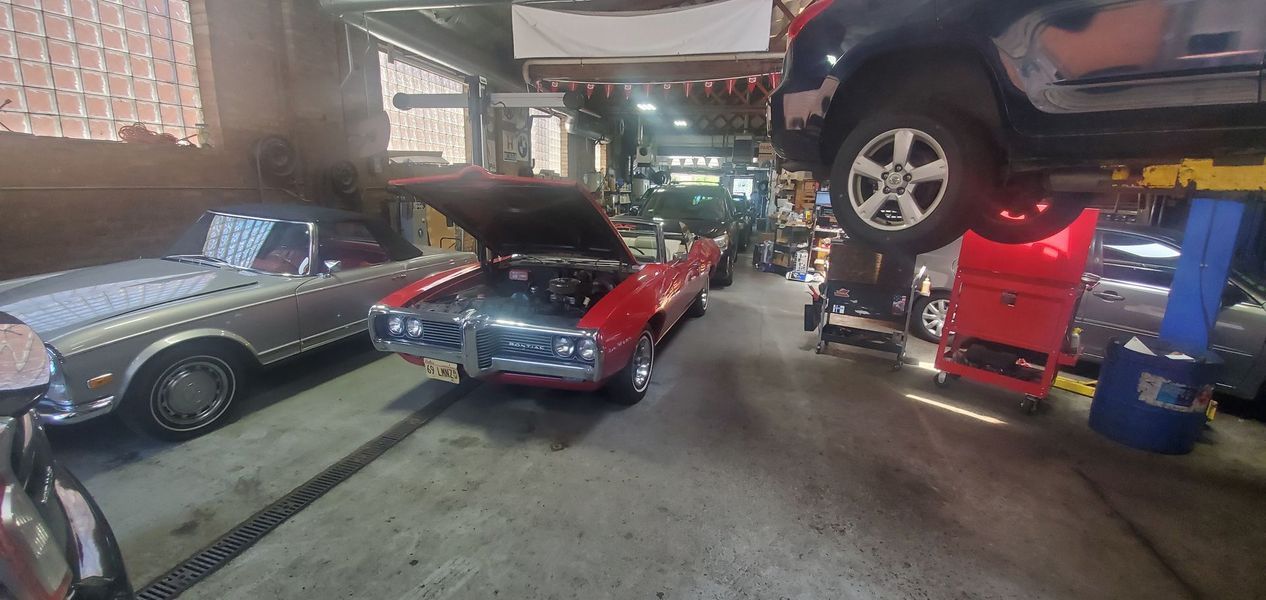 A red car is parked in a garage with its hood open.