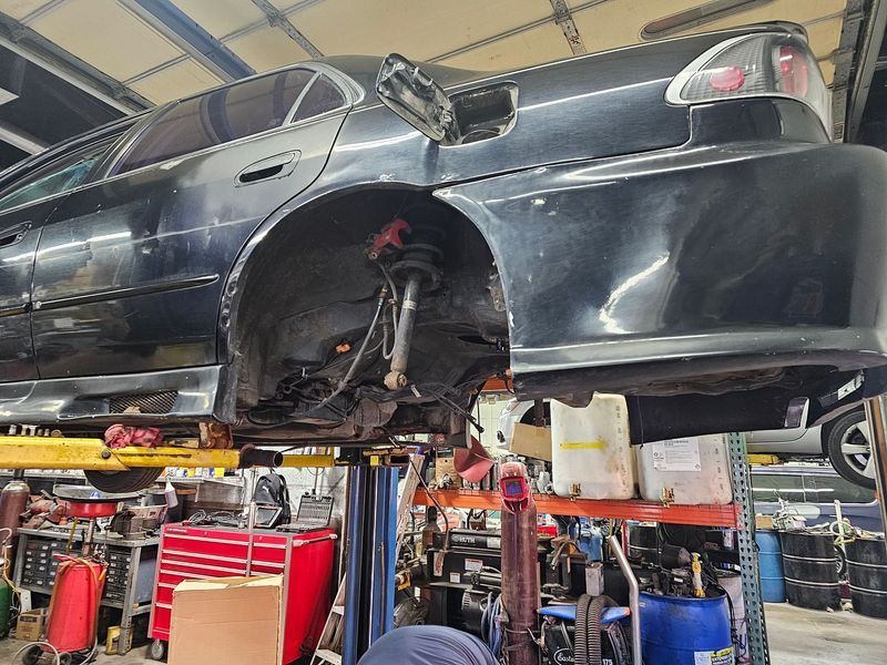 A black car is sitting on a lift in a garage.