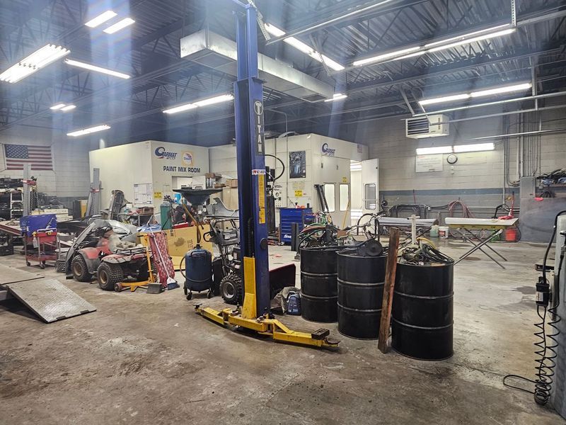 A garage with a lot of barrels and a lift.