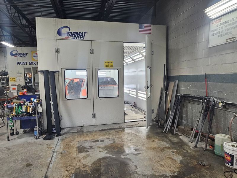 A car is being painted in a paint booth in a garage.