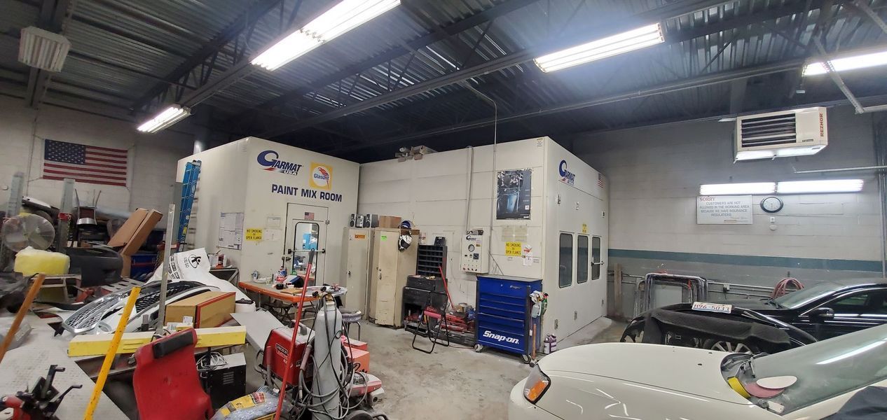 A car is being painted in a garage with a lot of tools.