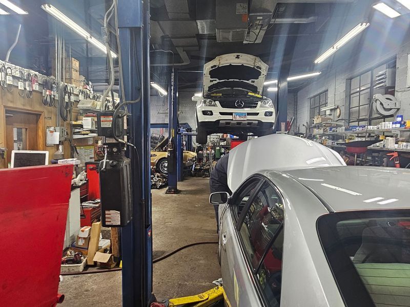 A white car is sitting on a lift in a garage.