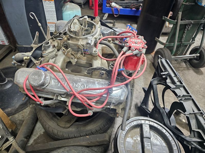 A car engine is sitting on top of a pile of tires in a garage.