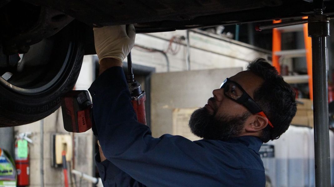 A man is working under a car in a garage.
