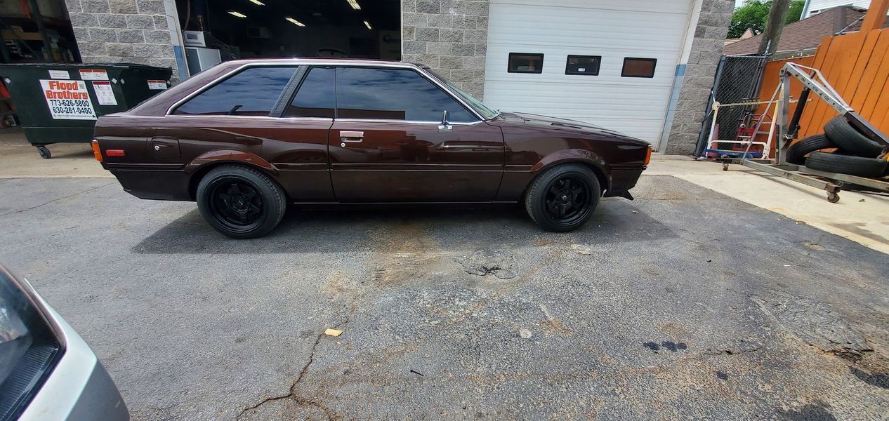 A brown car is parked in front of a garage door.