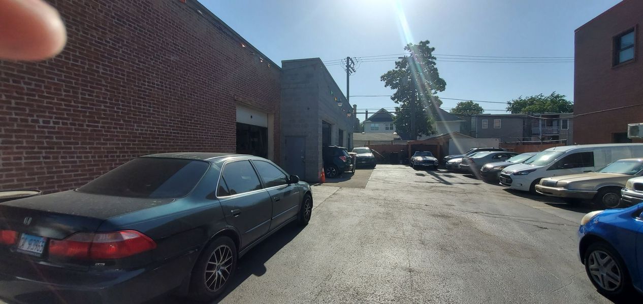 A blue car is parked in a parking lot next to a brick building.