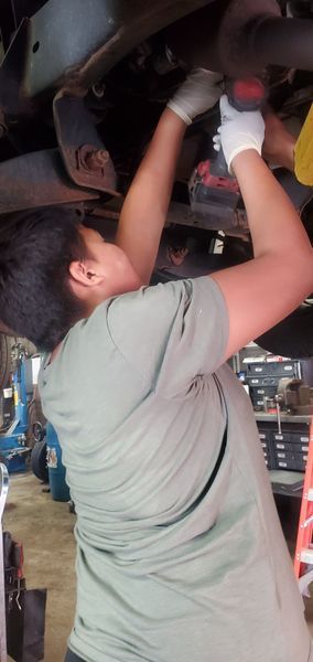 A man is working under a car with a drill