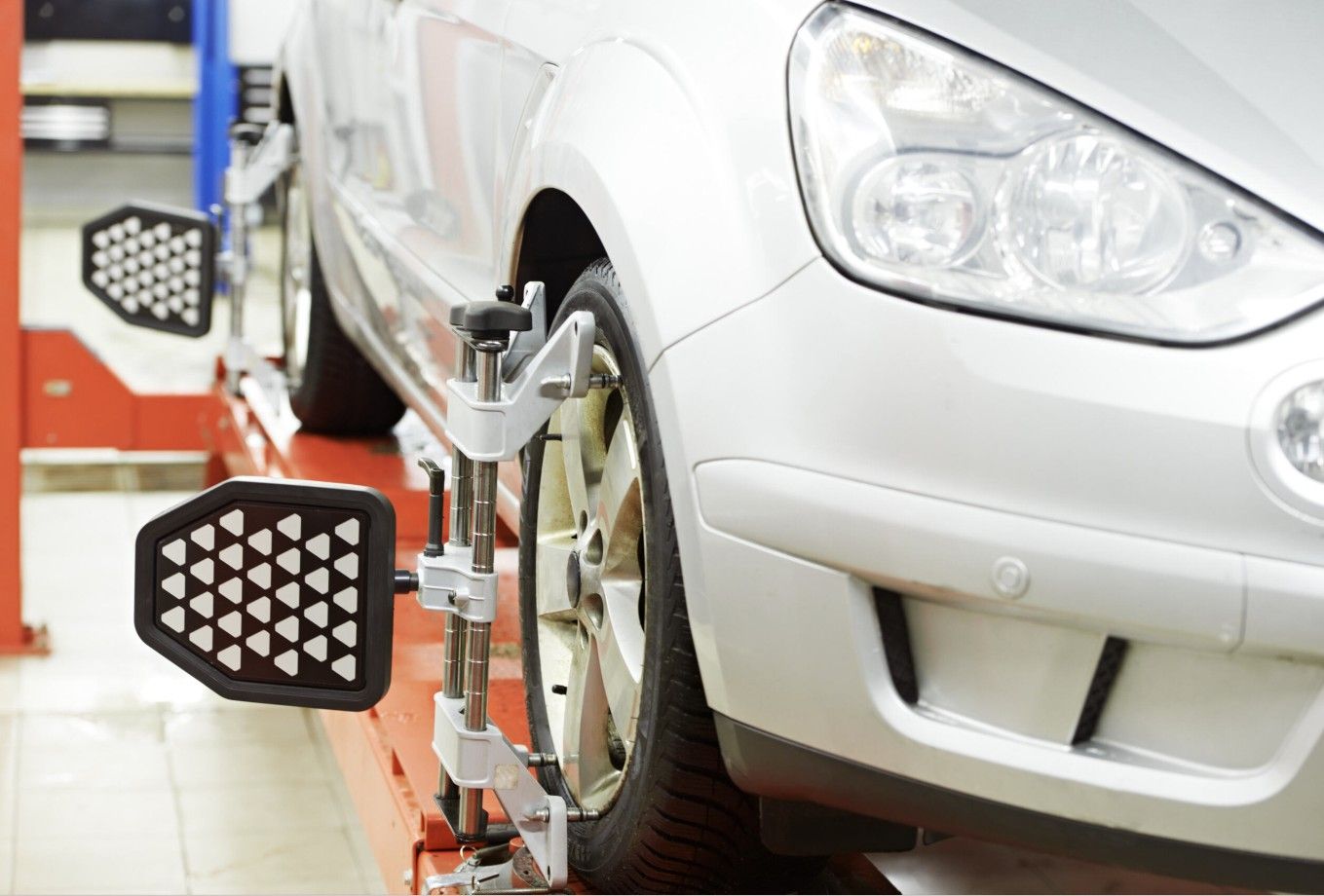 A car is being adjusted on a lift in a garage.