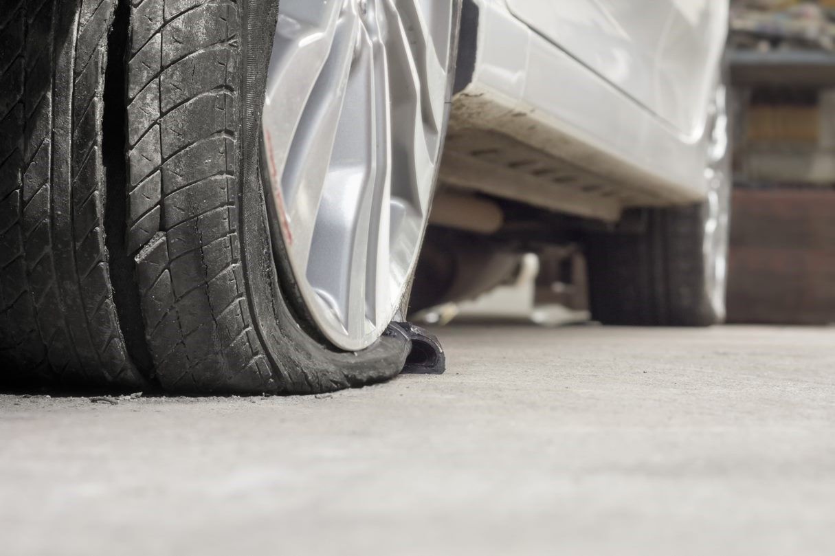 A close up of a flat tire on the side of a car.