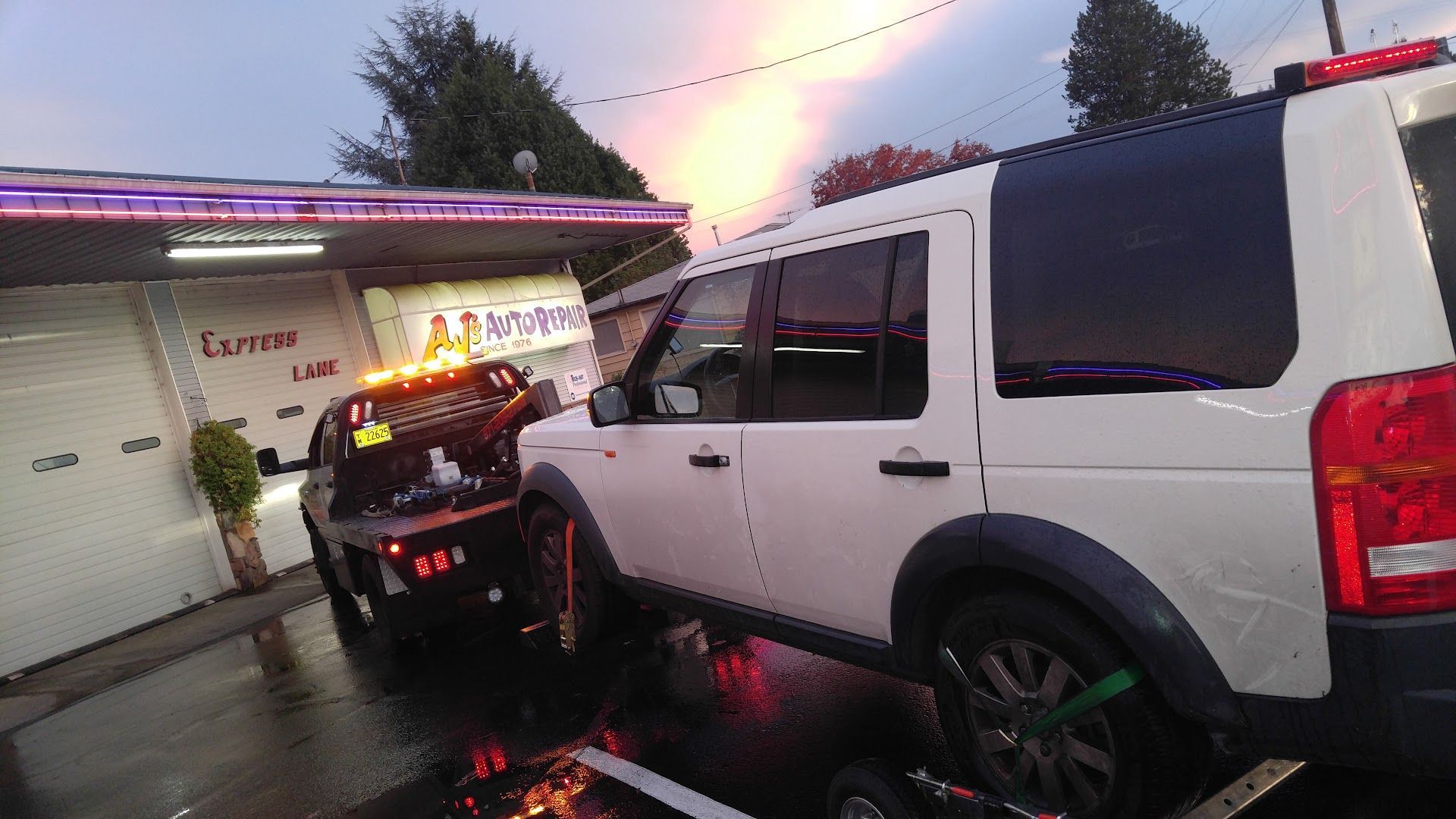 Vehicle Being Towed In Front Of Auto Repair Shop At Dusk | AJ’s Auto Repair