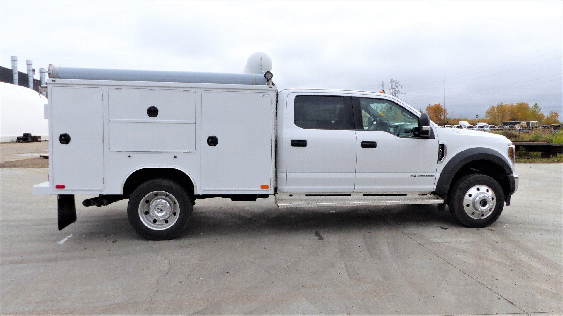 A white service truck is parked in a parking lot.