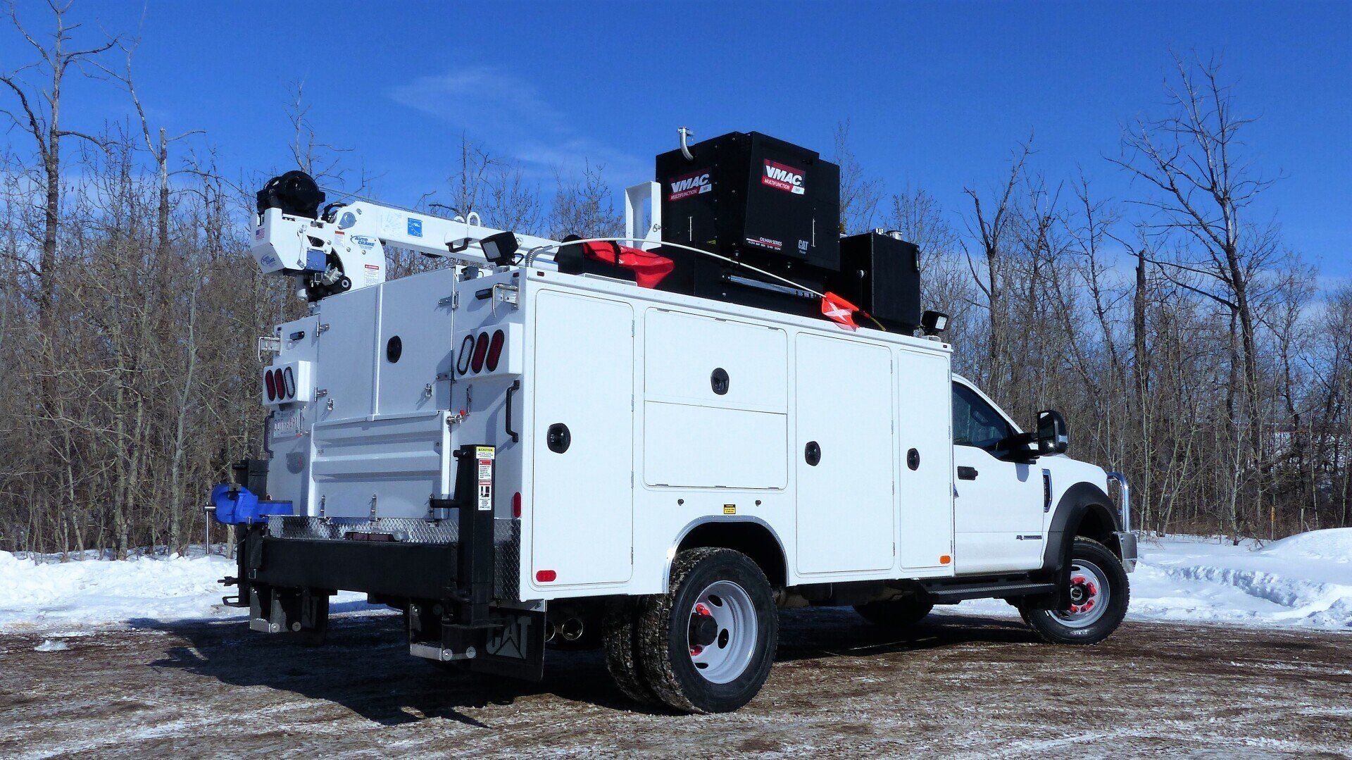 A white utility truck is parked in a snowy field.