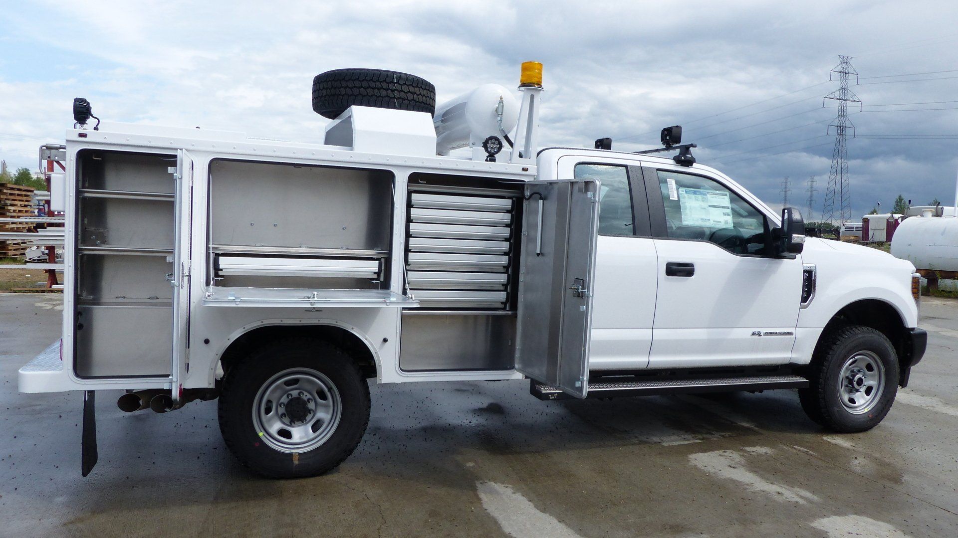 A white truck is parked in a parking lot with its doors open.