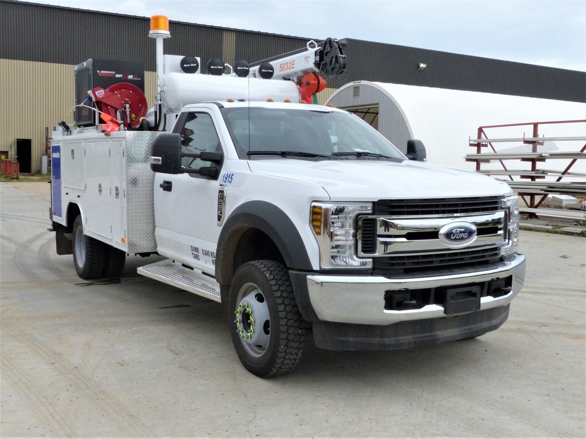 A white utility truck is parked in front of a building.