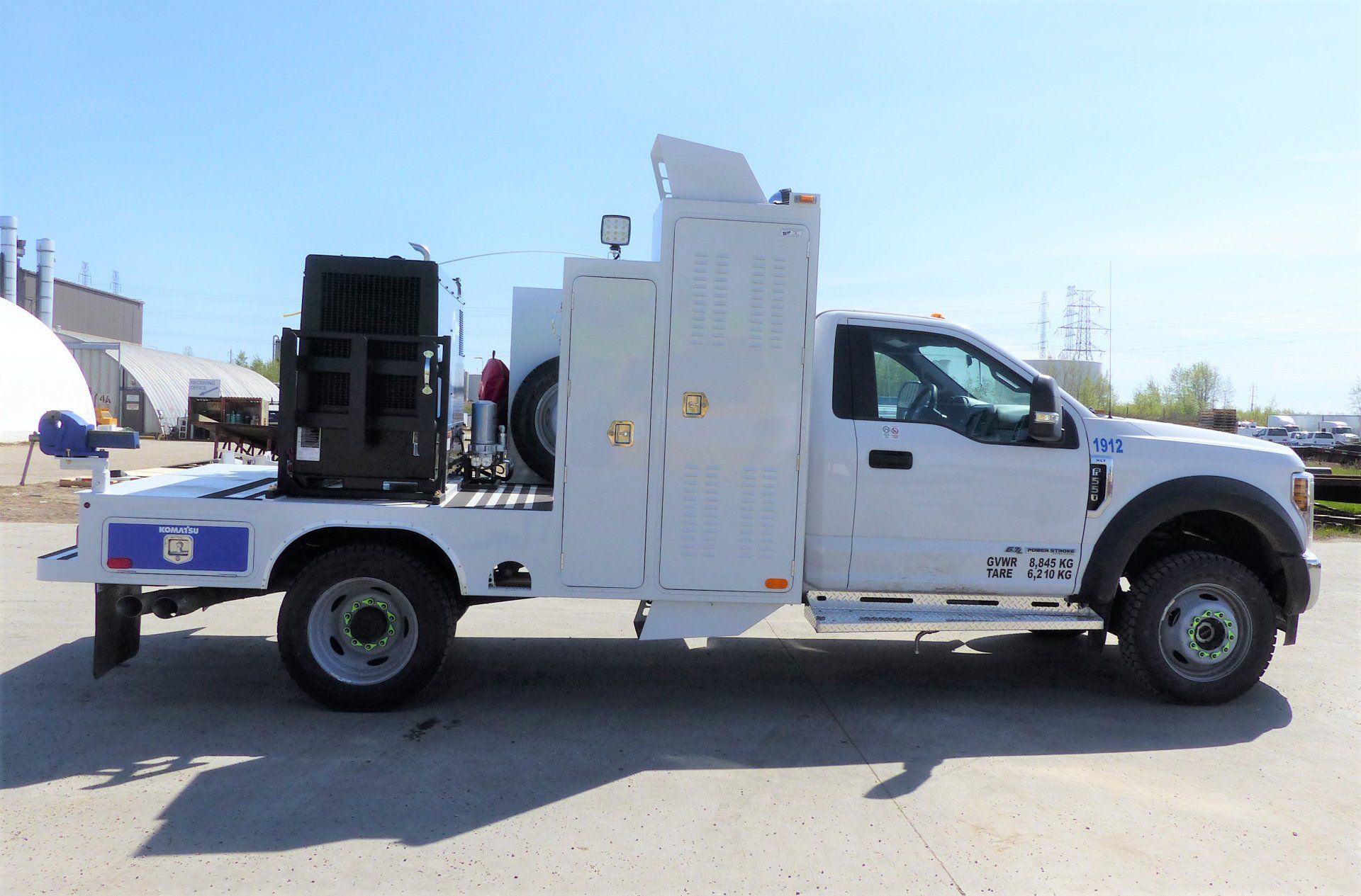 White service truck with equipment on a flatbed in an outdoor setting.