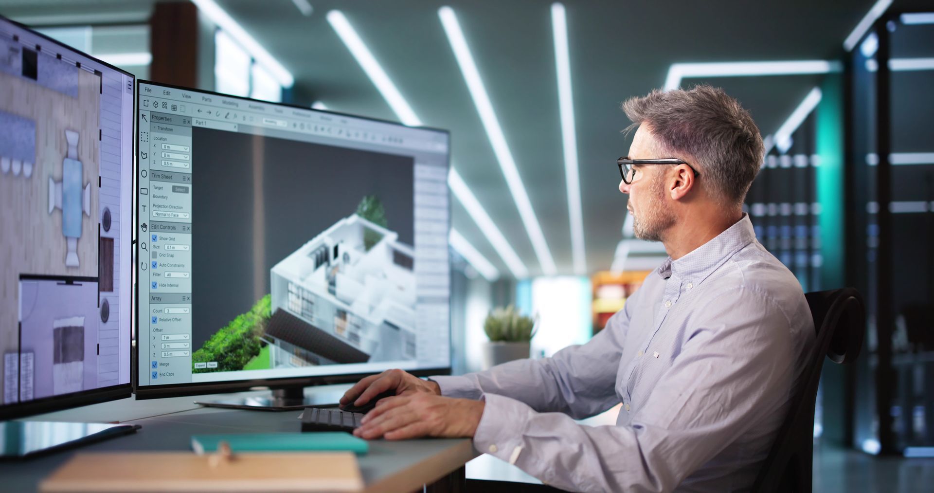 Designer working at dual monitors in a modern office, reviewing a 3D architectural model on screen