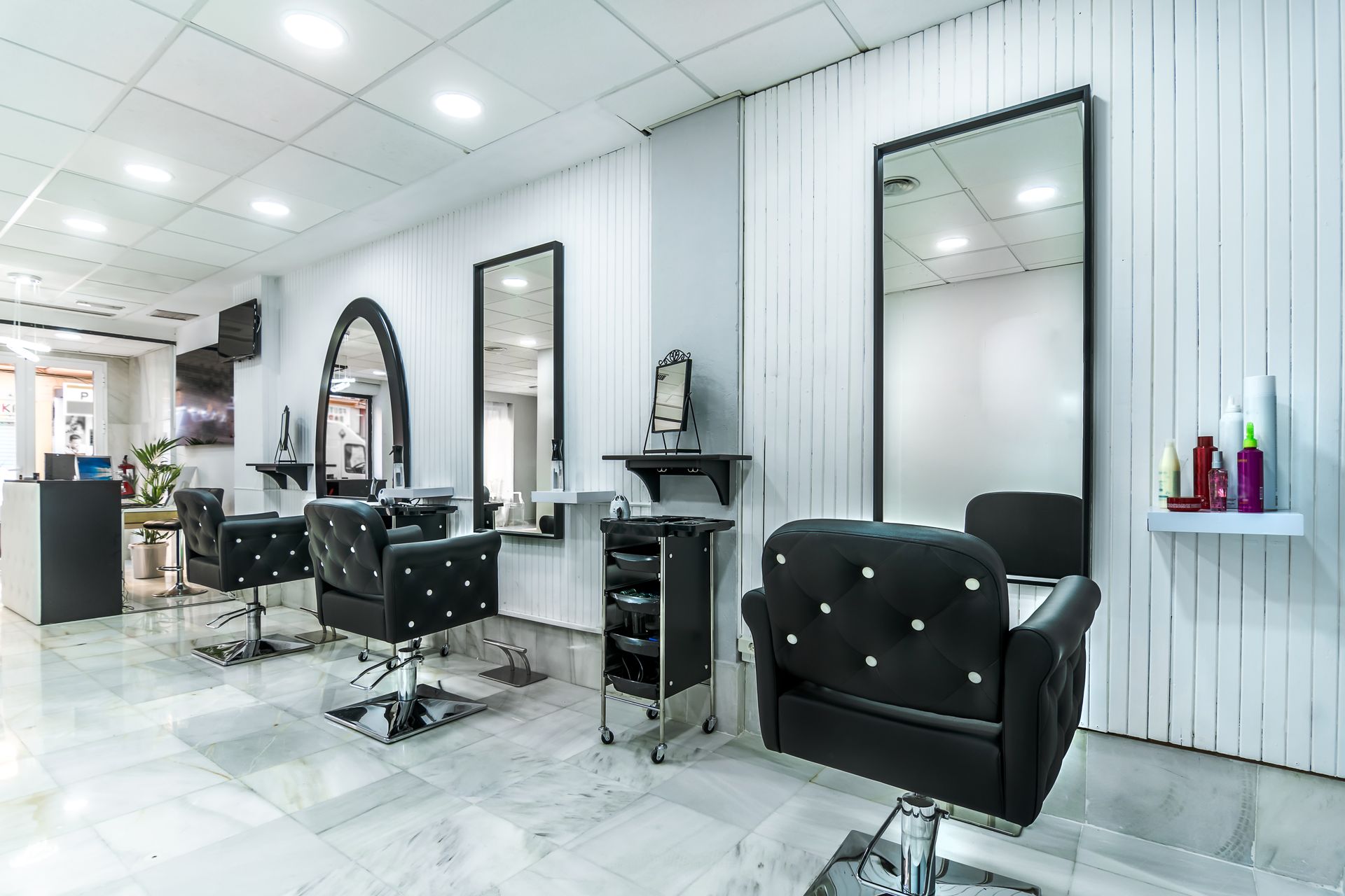 Empty modern salon with black styling chairs, mirrors, and white paneled walls