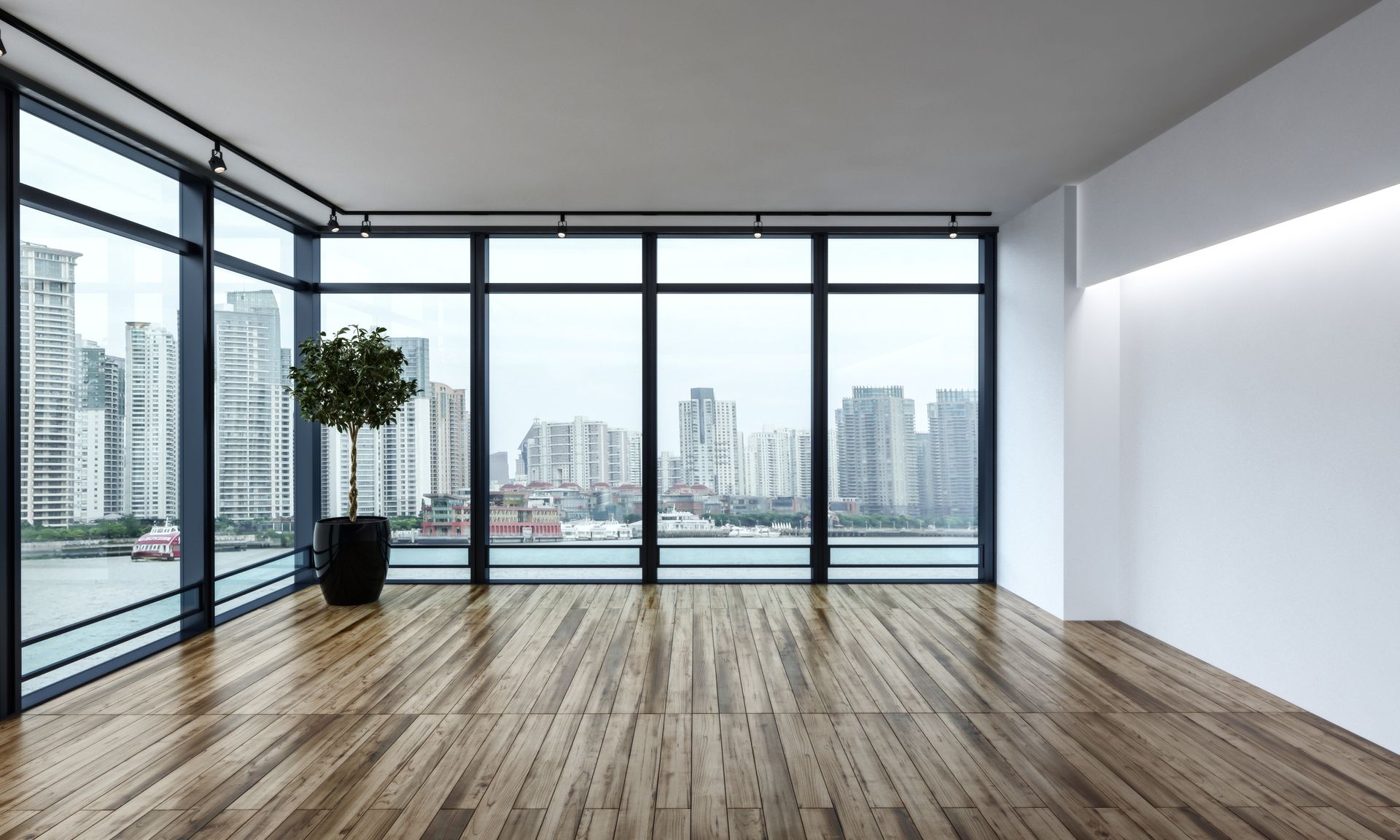 Empty modern apartment with large windows, wood floors, and city skyline view