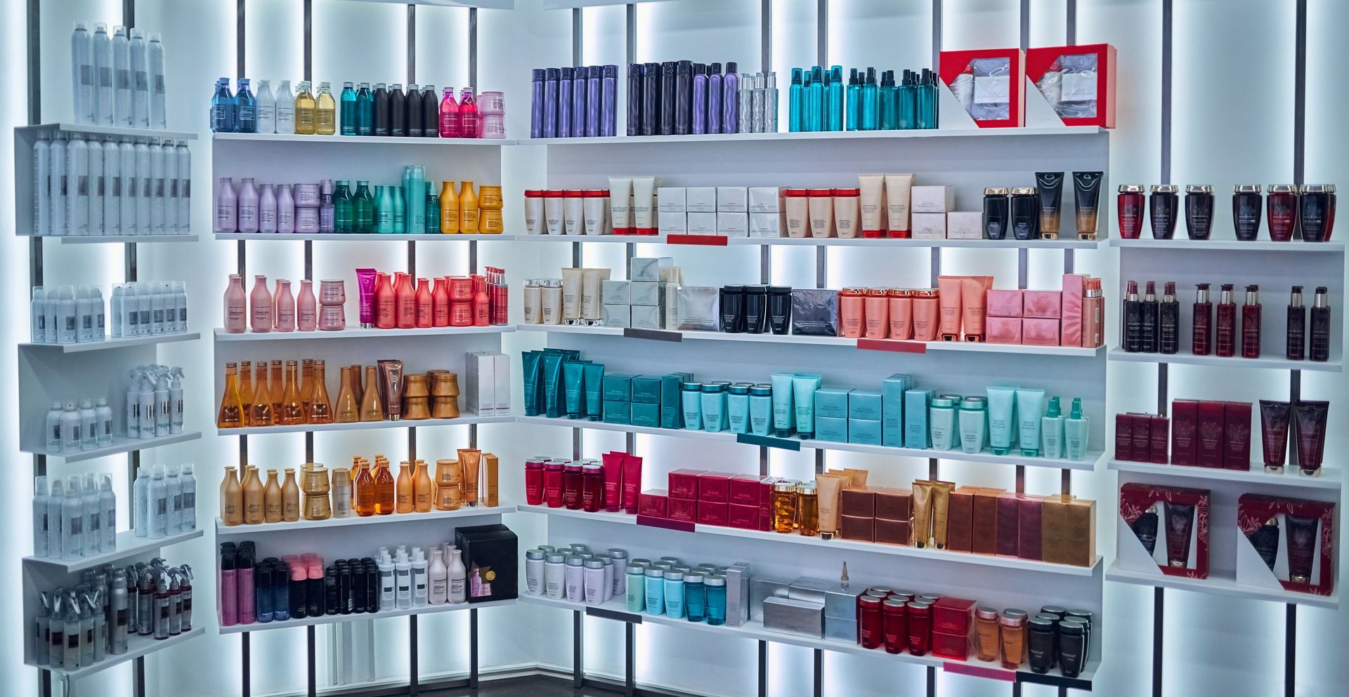 Wall of neatly arranged beauty products in colorful bottles and boxes on white shelves